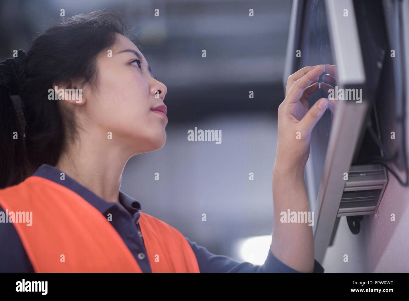 Young female engineer working on touchscreen computer monitor in an
