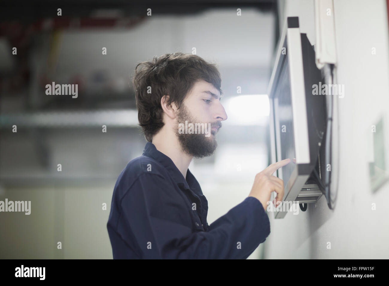 Young male engineer working on touchscreen computer monitor in an