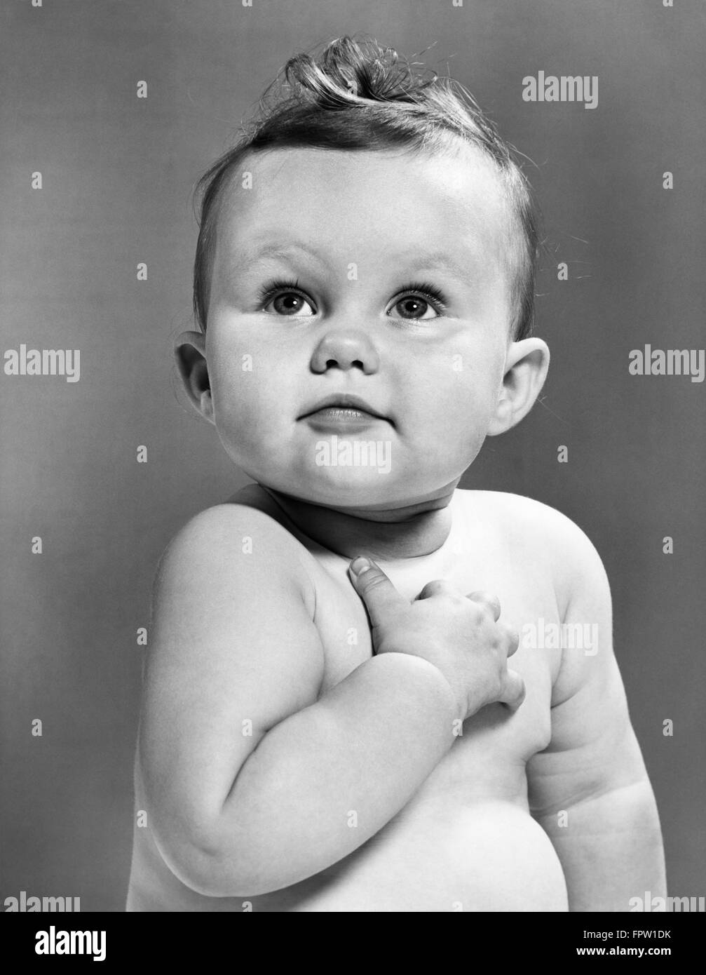 1950s BABY LOOKING UP HOLDING RIGHT HAND OVER HEART PLEDGE Stock Photo