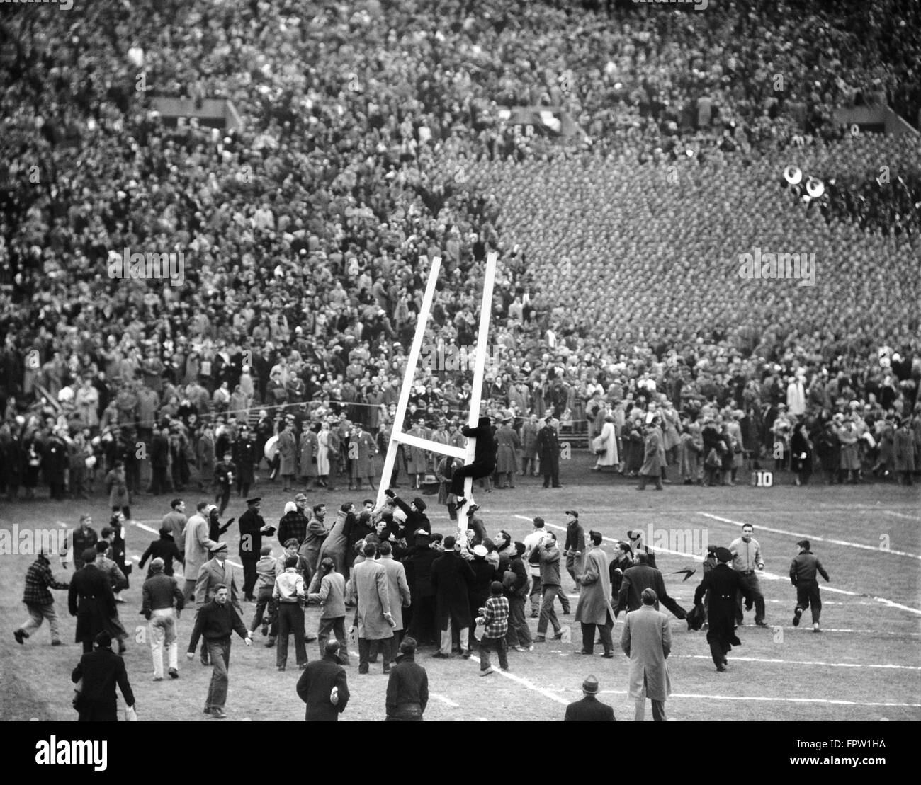 1950s ARMY NAVY GAME EXCITED SPECTATORS CROWD TEARING DOWN GOAL POSTS NAVY WON THE GAME Stock Photo