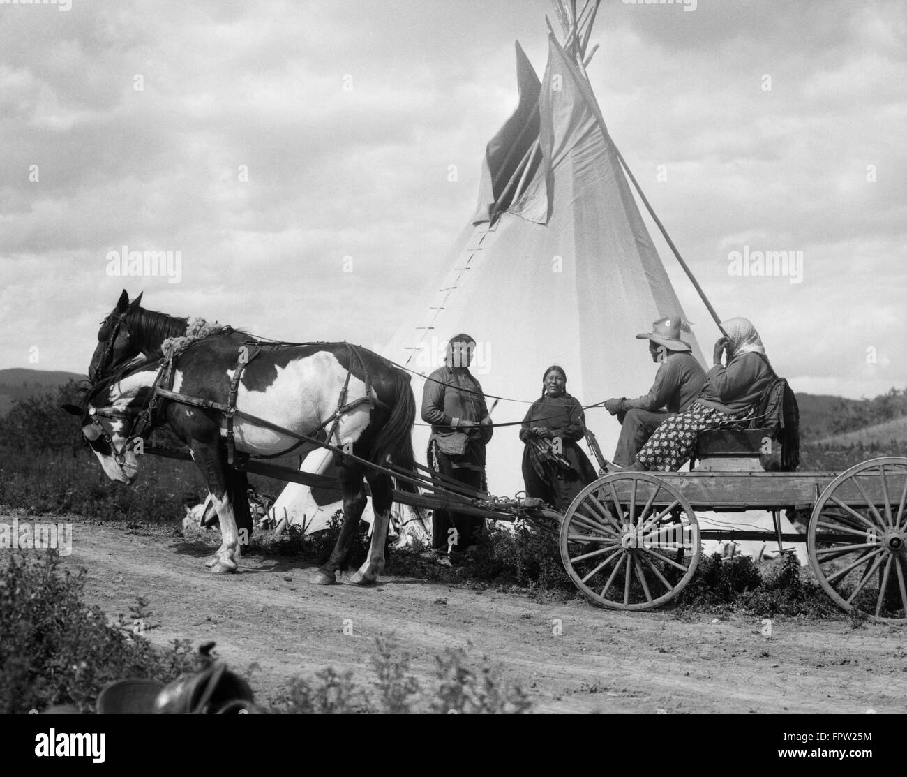 1920s TWO NATIVE AMERICAN INDIAN COUPLES VISITING BY TEPEE ONE COUPLE IN HORSE AND WAGON STONEY SIOUX TRIBE ABLERTA CANADA Stock Photo
