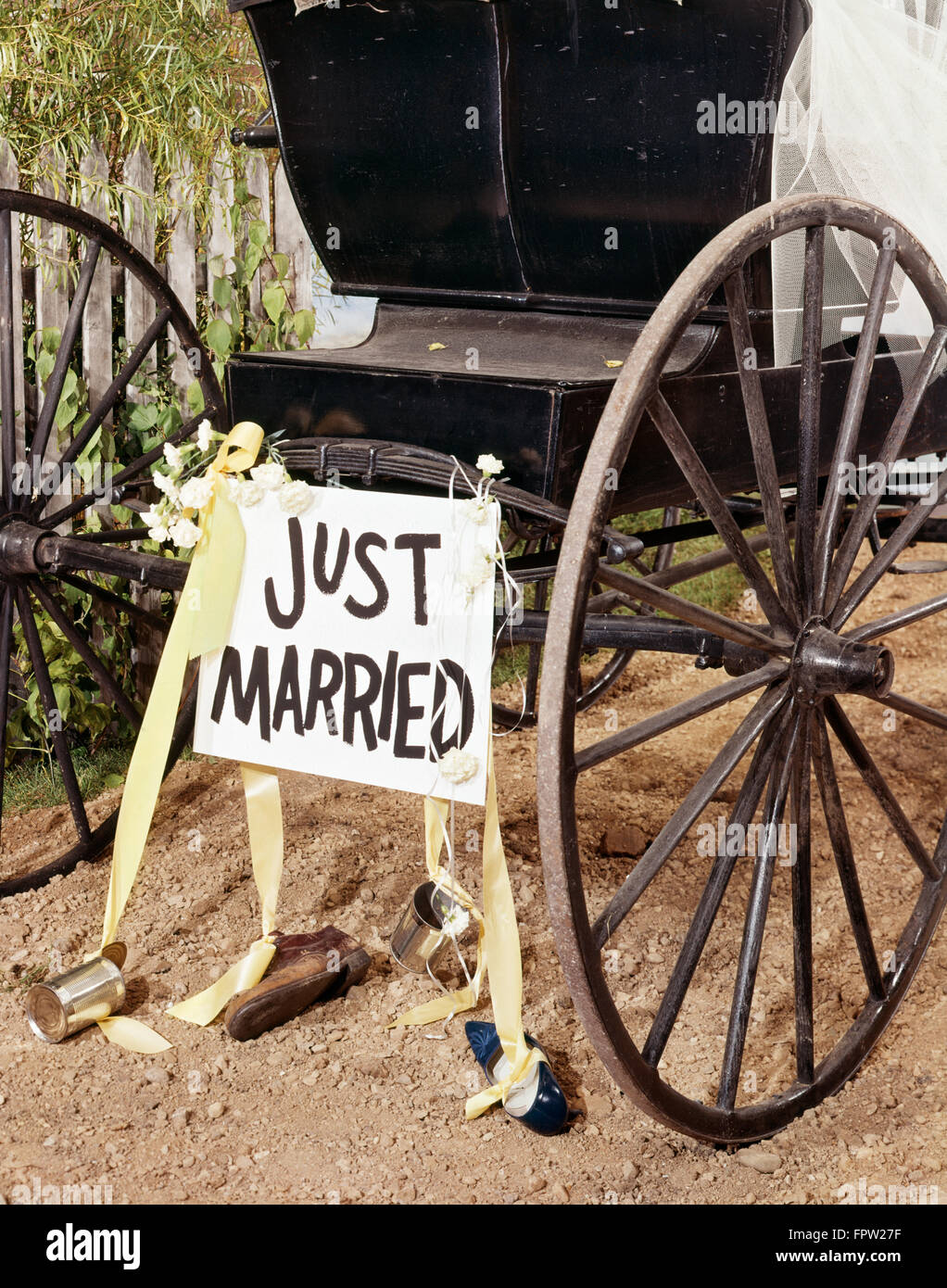 1970s HORSE DRAWN BUGGY WITH JUST MARRIED SIGN SHOES AND TIN CANS TIED ON WITH YELLOW RIBBON BRIDAL VEIL INSIDE BUGGY Stock Photo