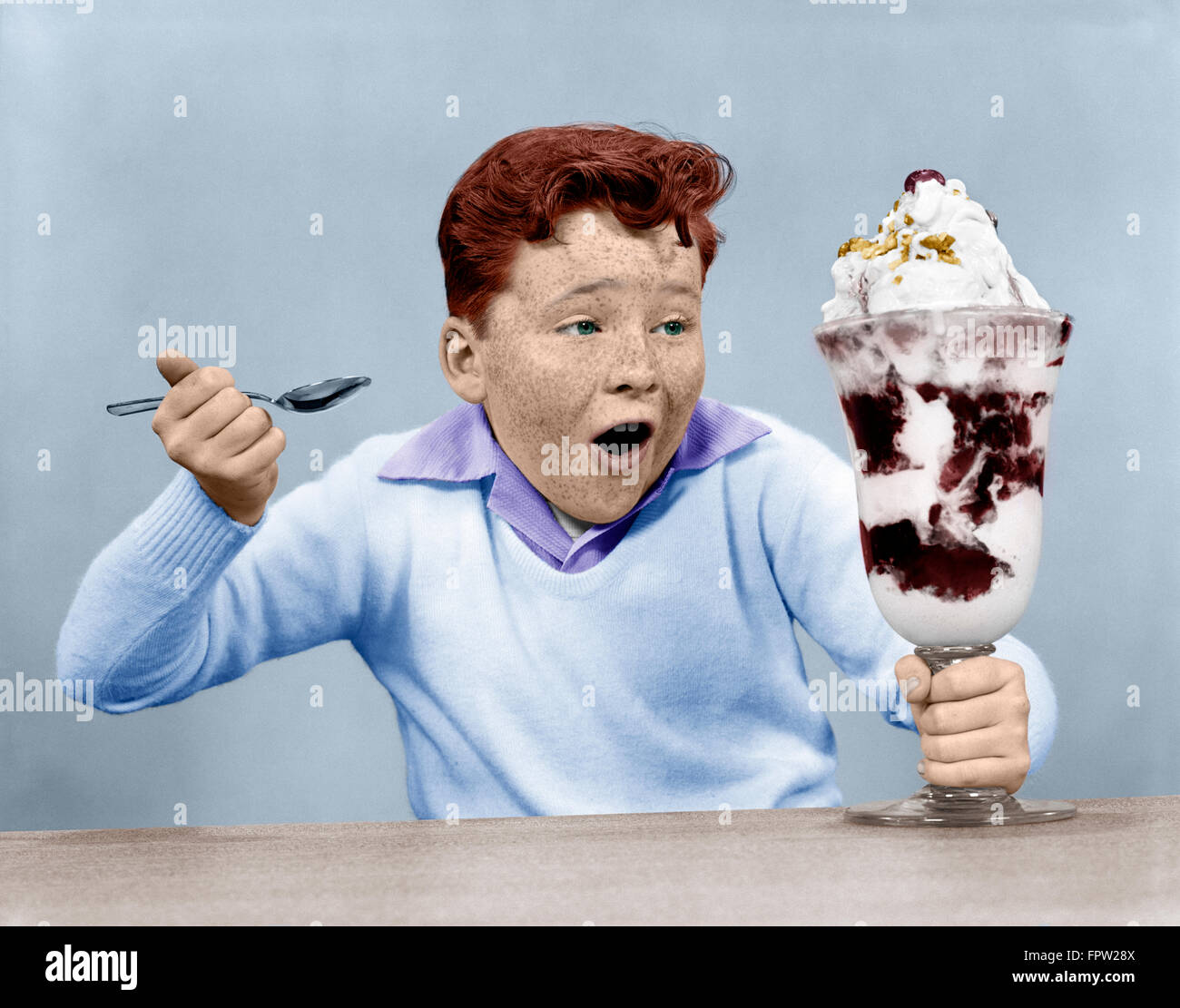 1950s FRECKLE FACE BOY DIGGING INTO GIANT ICE CREAM SUNDAE Stock Photo