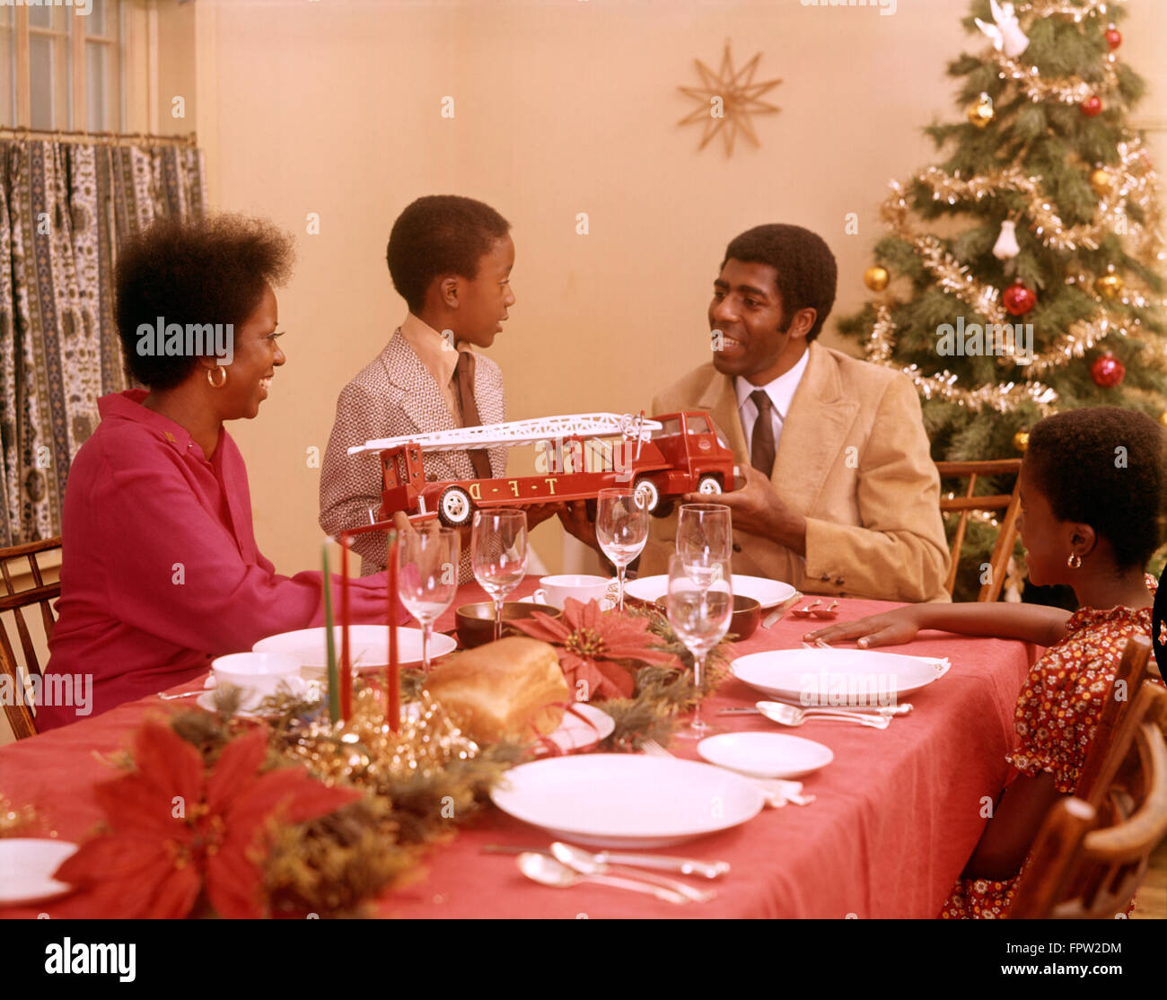 1970s AFRICAN AMERICAN FAMILY AT CHRISTMAS HOLIDAY DINNER TABLE FATHER MOTHER SON AND DAUGHTER Stock Photo