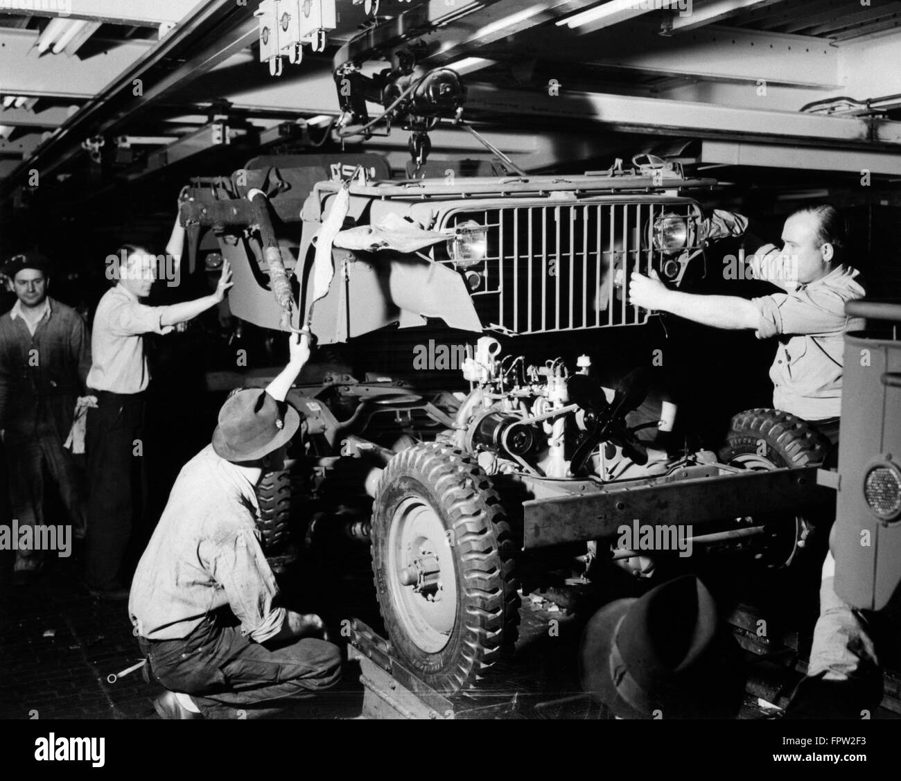 1940s DEFENSE WORKERS AUTOMOBILE ASSEMBLY LINE DROP BODY ONTO CHASSIS BLITZ BUGGY JEEP FORD RIVER ROUGE PLANT DETROIT MI USA Stock Photo