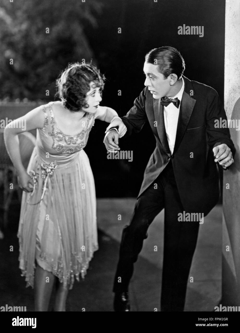 1920s COUPLE MAN WOMAN FORMAL EVENING CLOTHES DANCING OR STEPPING LIGHTLY Stock Photo