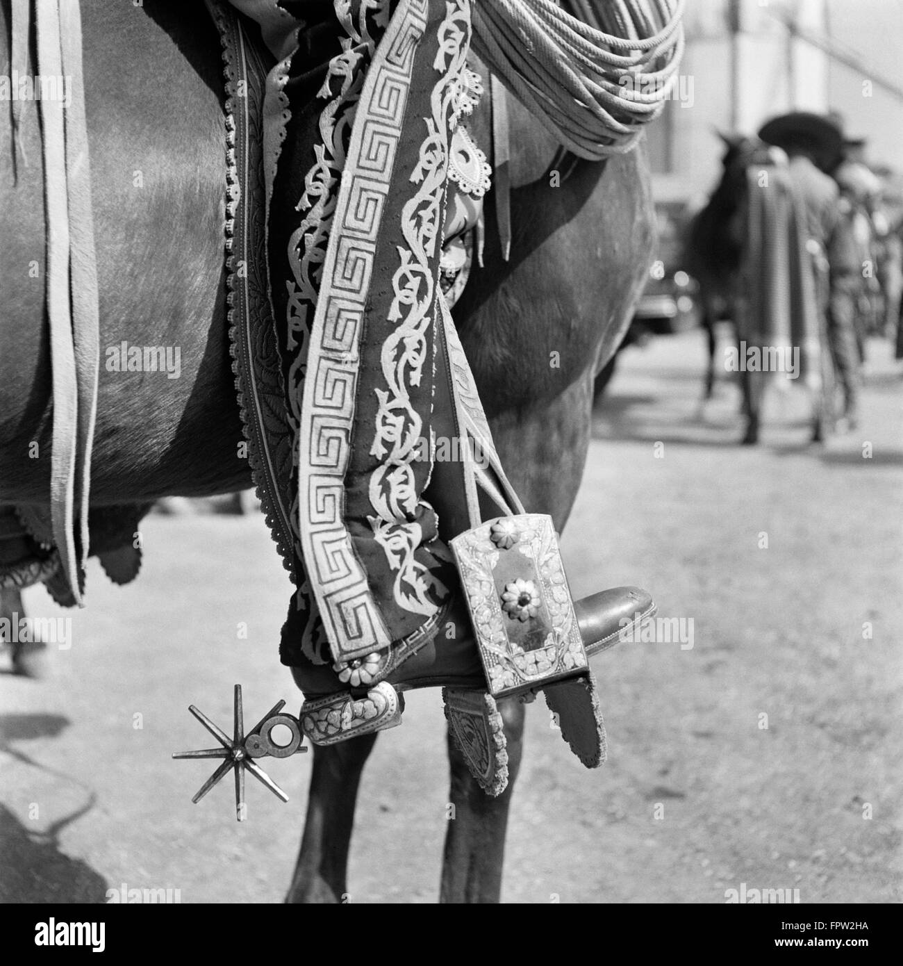 1930s DETAIL OF TRADITIONAL CHARRO COWBOY COSTUME EMBROIDERED CHAPS SPURS LEATHER BOOTS IN HORSES STIRRUP MEXICO Stock Photo