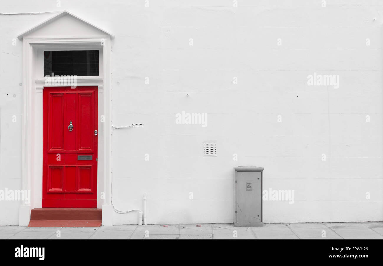 Bight red wooden door with silver mail door slot and door knocker on a white wall Stock Photo