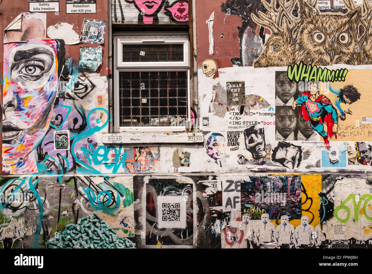 Wall covered in graffiti and wallpaper murals in the trendy area near Brick lane, Shoreditch, East London. Stock Photo