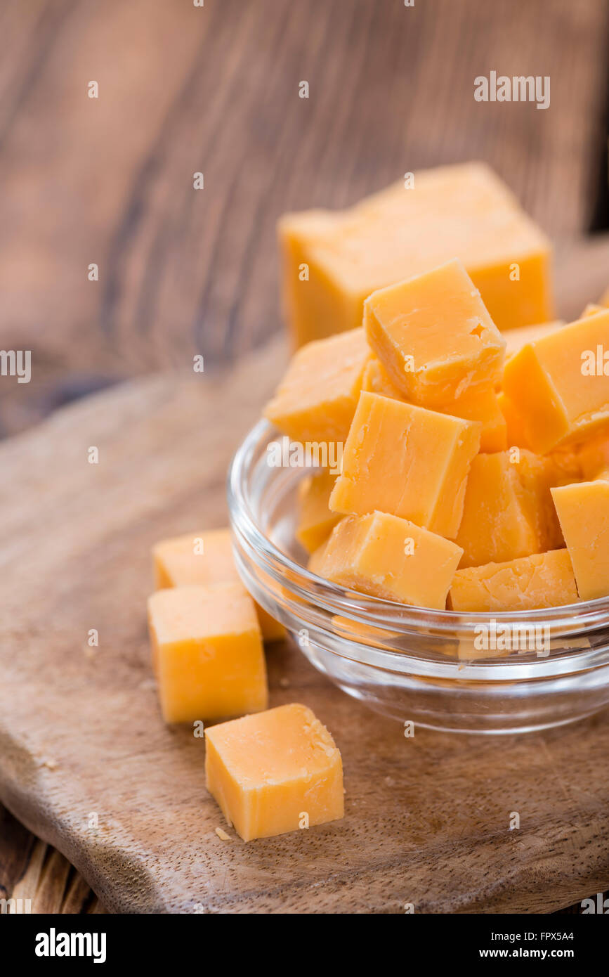 Diced Cheddar (close-up shot) on rustic wooden background Stock Photo