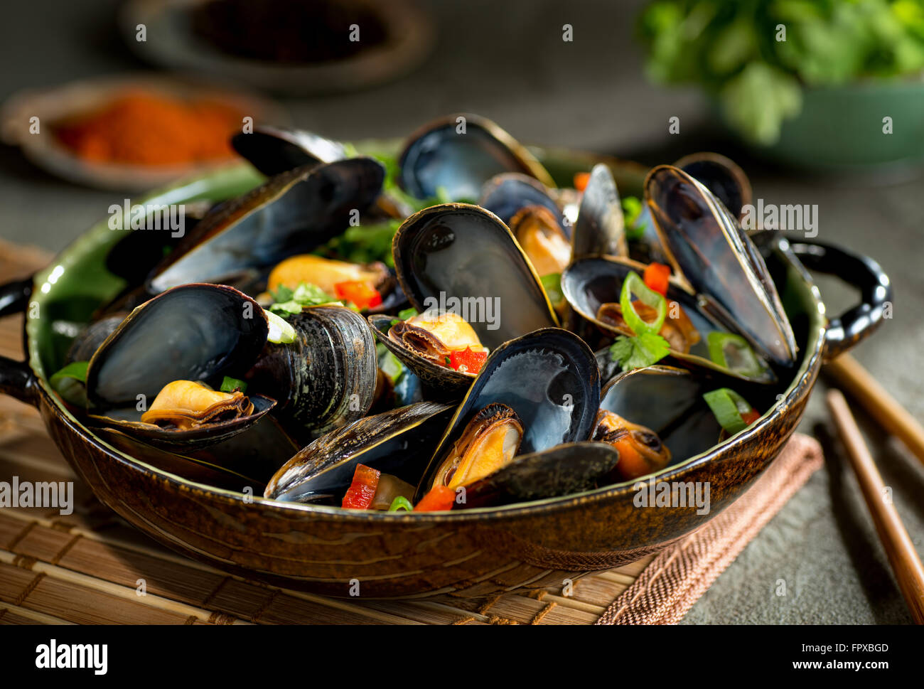 Delicious asian style steamed mussels with red pepper, green onion, and coriander in a coconut broth. Stock Photo