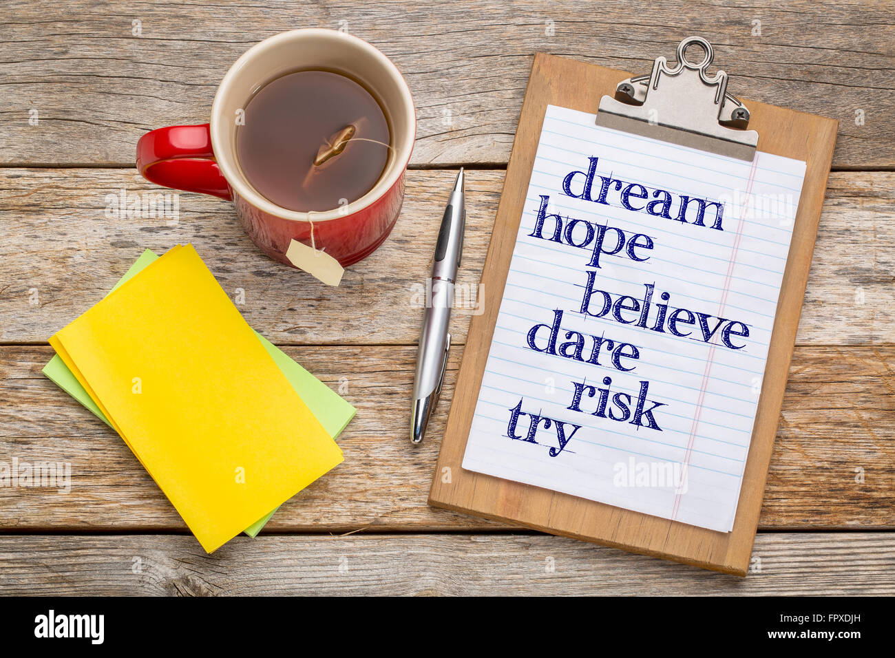 Dream, hope, believe, dare, risk and try - inspirational words on clipboard  with a pen, tea and sticky notes against rust wood  Stock Photo