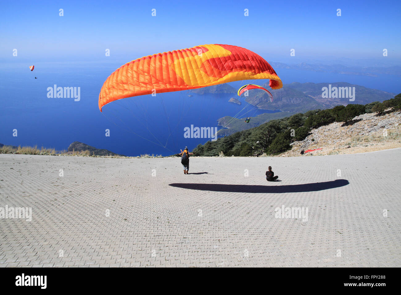Paragliders paragliding off Babadag mountain to land in Oludeniz near Fethiye Turkey Stock Photo