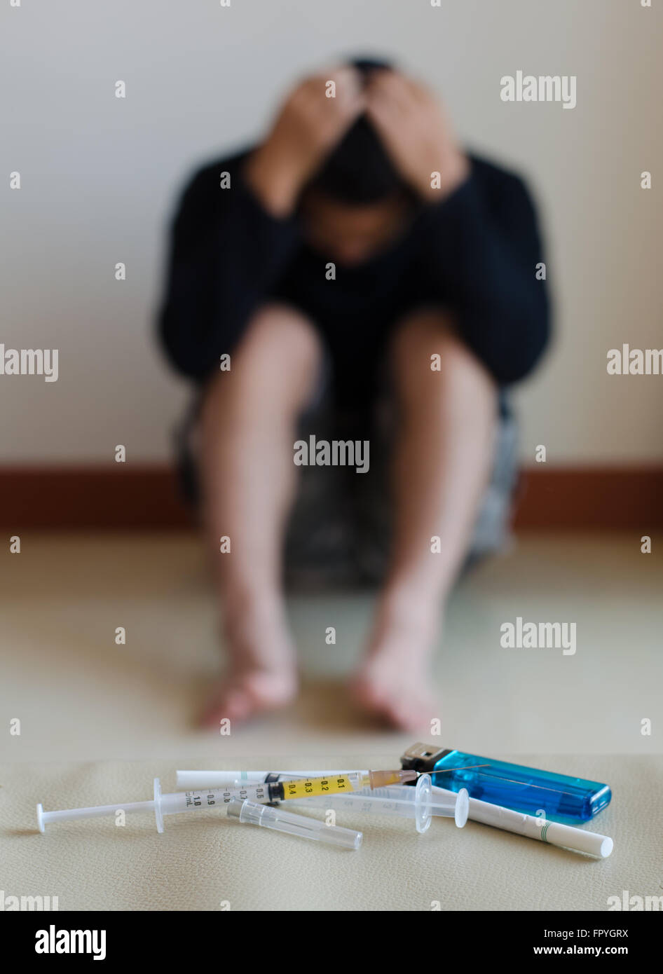 syringe and drug addict, sitting in the background Stock Photo