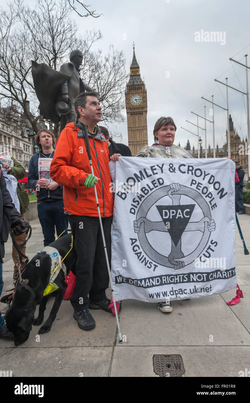 London, UK. 19th March, 2016. Paula Peters holds the Bromley and Croydon Disabled People Against Cuts (DPAC) banner next to Roger Lewis of South London DPAC at the celebration of the resignation of Iain Duncan Smith, one of the chief architects of the brutal Tory welfare policy that has caused them so much suffering and harm, with a party in Parliament Square. They have little hope that his successor in office will ease the persecution of the sick and disabled. Peter Marshall/Alamy Live News Stock Photo