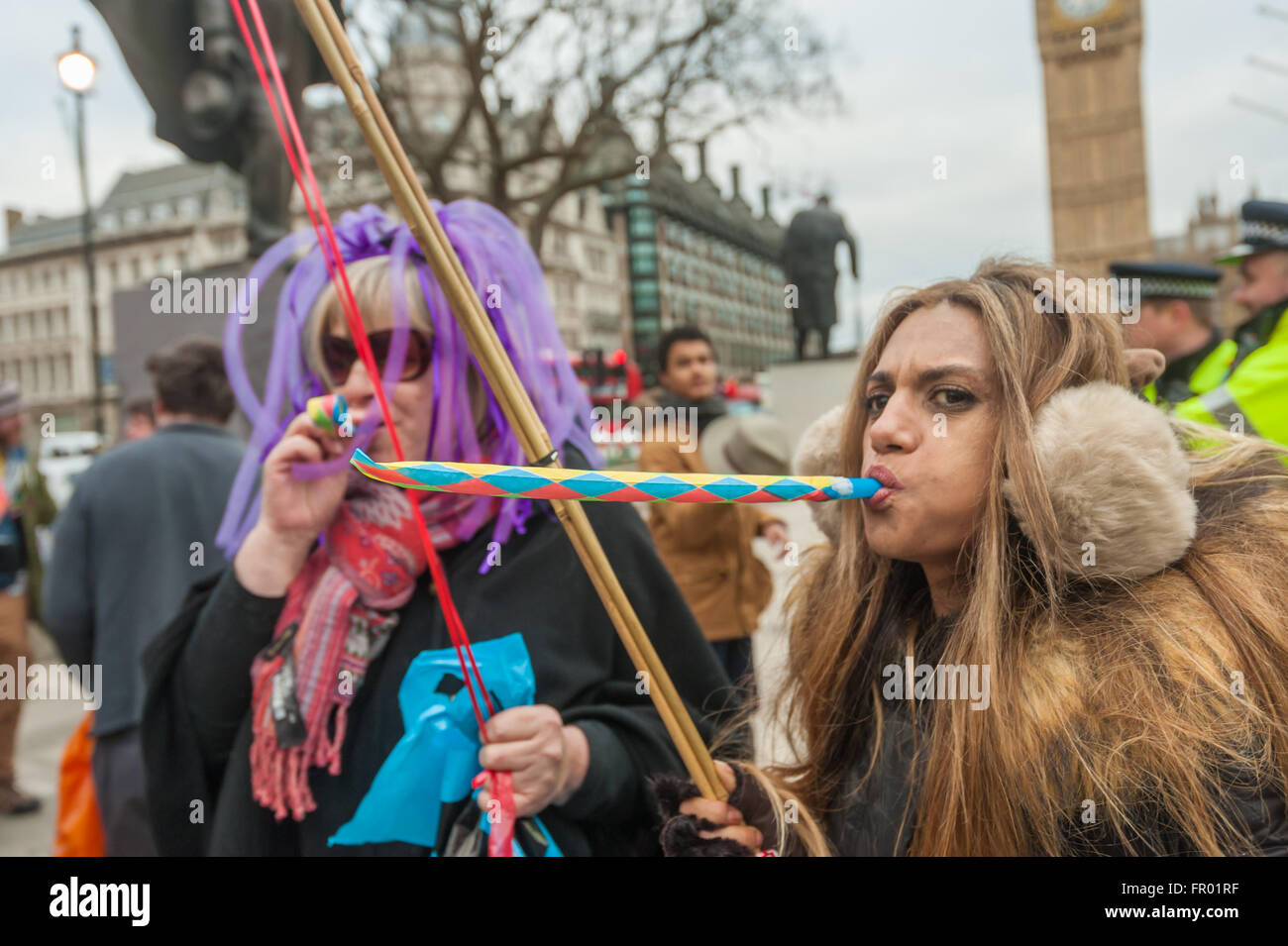 London, UK. 19th March, 2016. Women blow out party squakers as Disabled People Against Cuts (DPAC) celebrate the resignation of Iain Duncan Smith, one of the chief architects of the brutal Tory welfare policy that has caused them so much suffering and harm, with a party in front of the Houses of Parliament in Parliament Square. . Peter Marshall/Alamy Live News Stock Photo