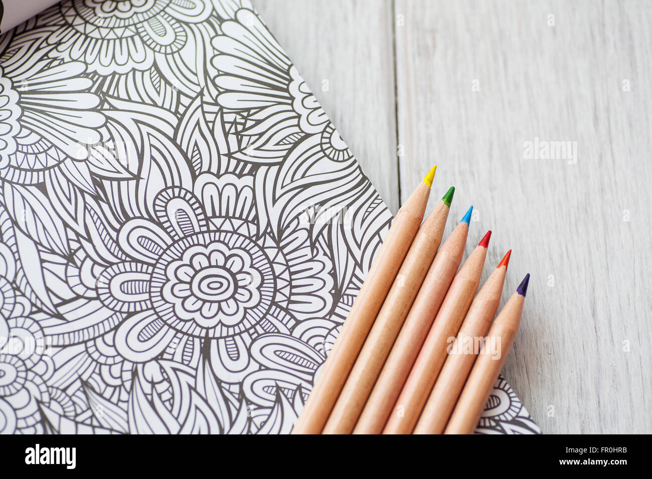 Person coloring in an adult coloring book with colorful pencil