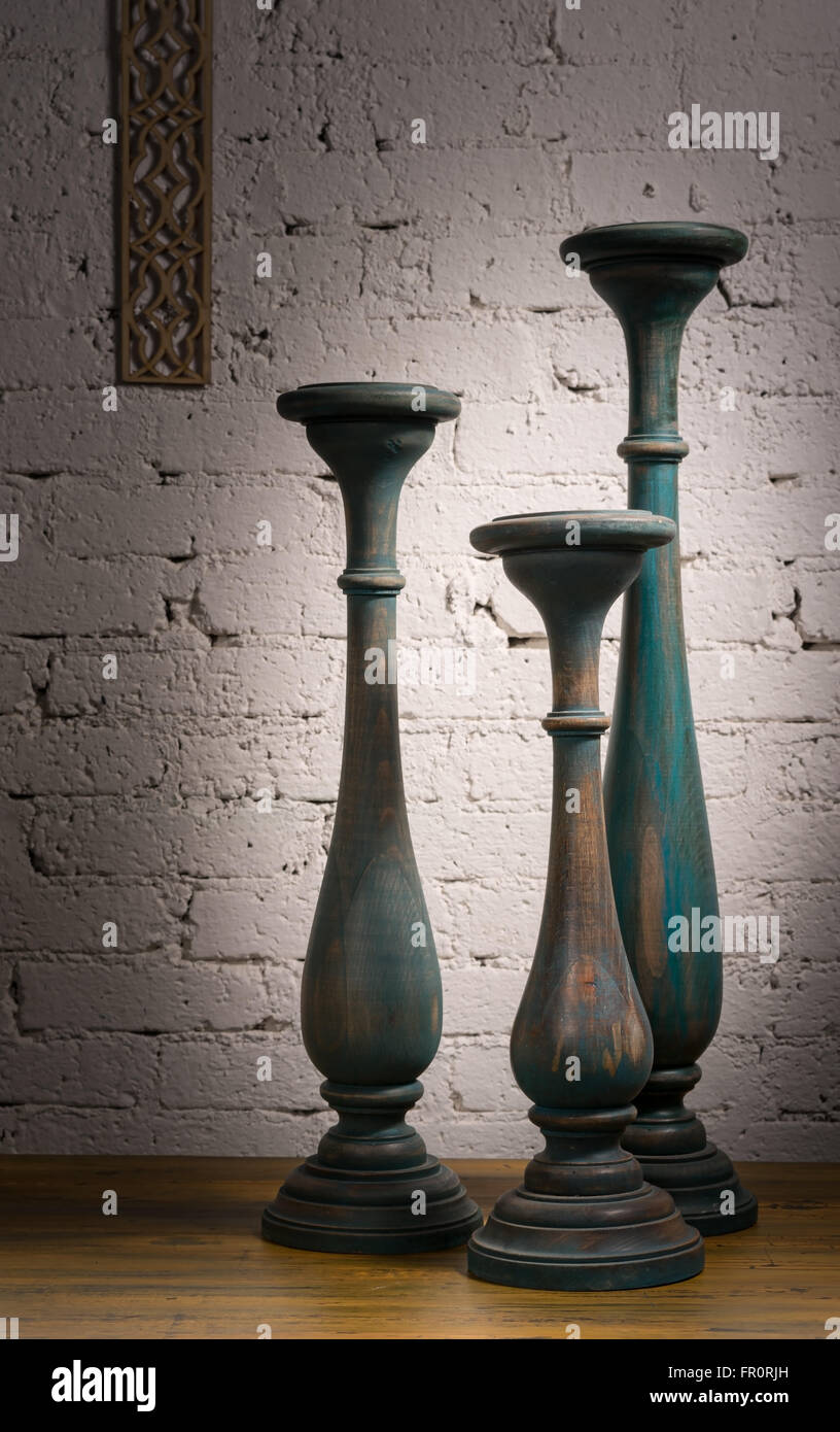Composition of three blue gray vintage wooden candlesticks on a background of wooden floor and