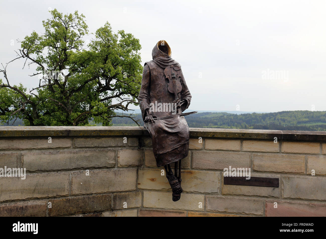 Monk Maurus with a violin sitting on the wall around the church in parish church of St. James in Hohenberg, Germany Stock Photo