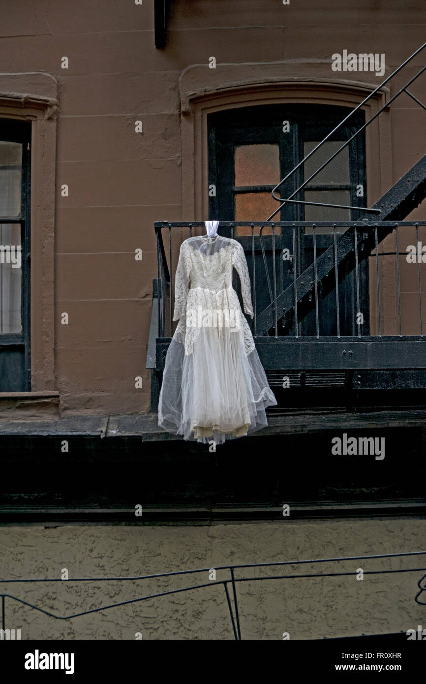 A white wedding dress hanging from a fire escape on 18th Street in the Chelsea section of Manhattan, New York City Stock Photo