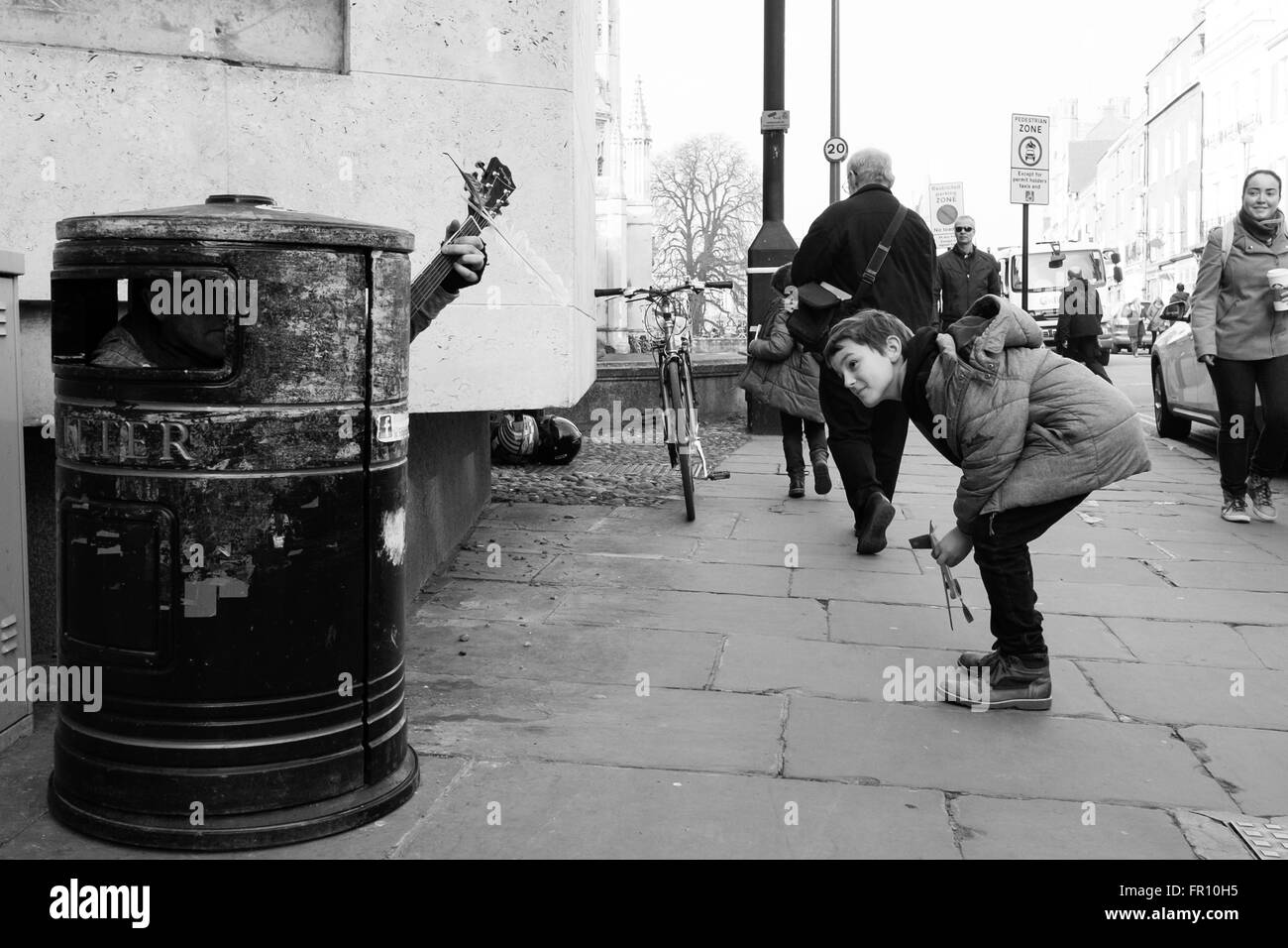 A child is amazed by a singing litter bin.  Street performer art guitar boy kid Stock Photo