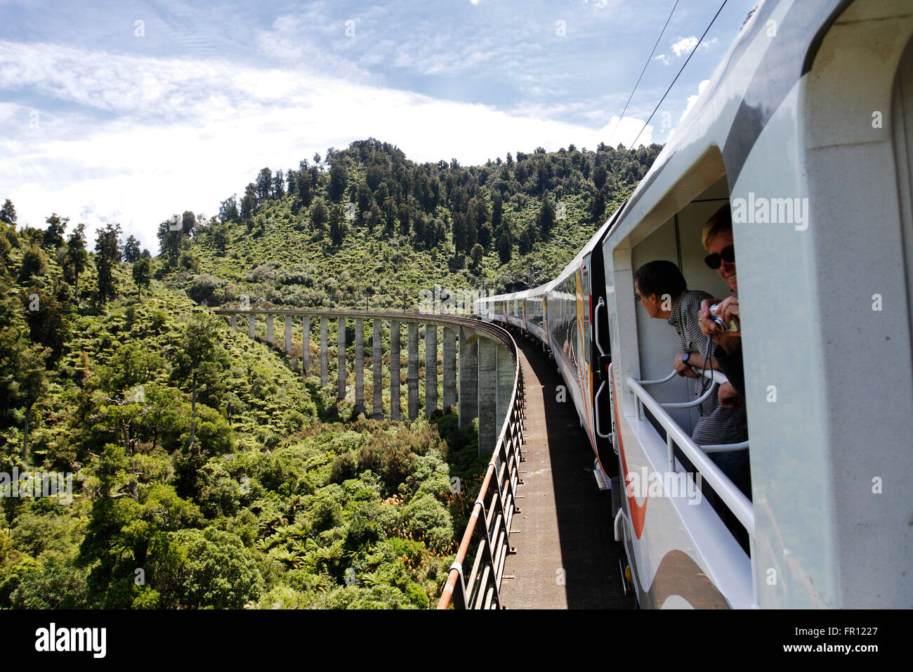Two passengers looking out from inside the open coach of Northern Explorer Train in New Zealand. Stock Photo