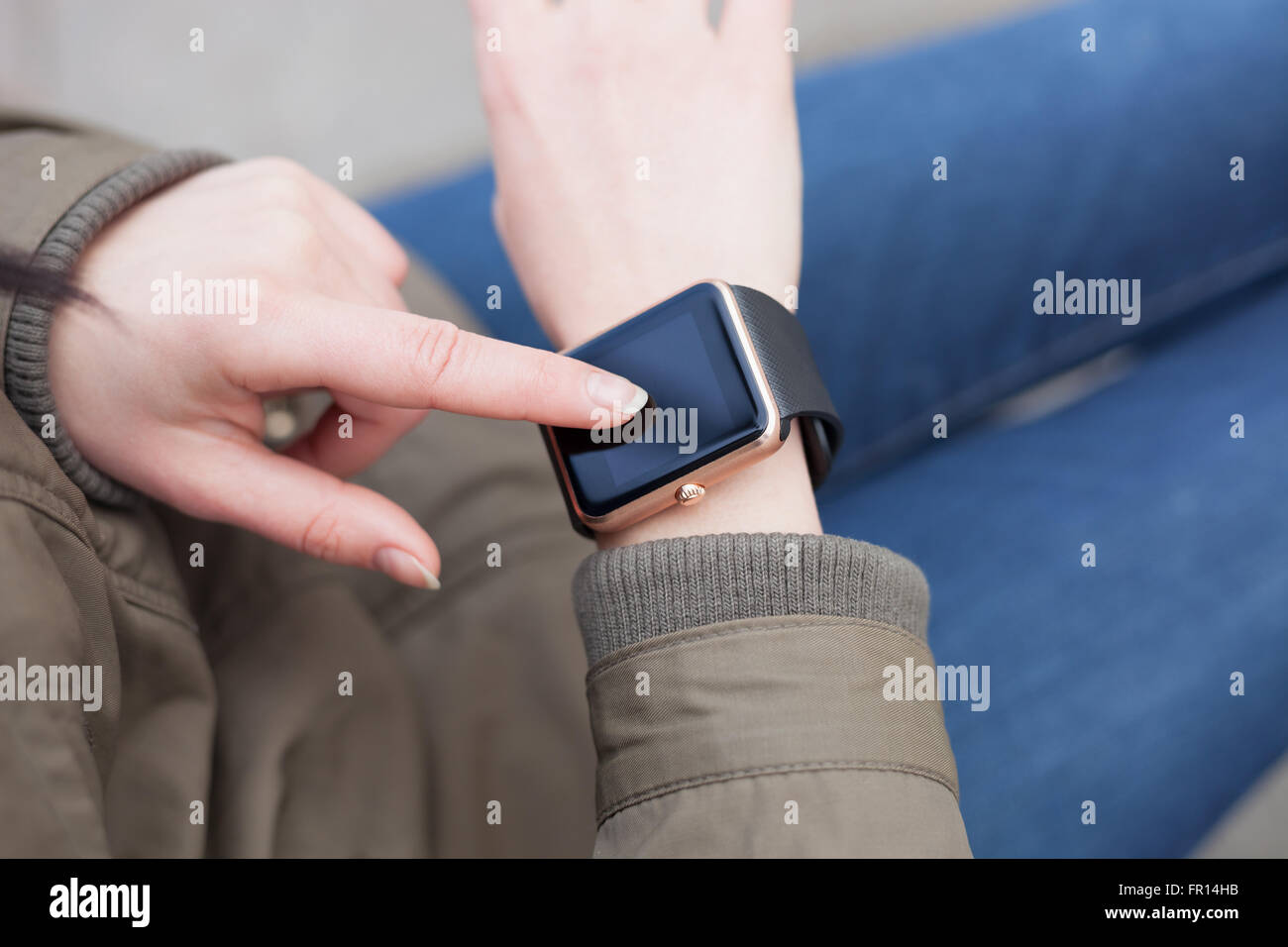 Female hand touching her trendy smart wrist watch with a finger. This person is always connected to social media and internet. Stock Photo