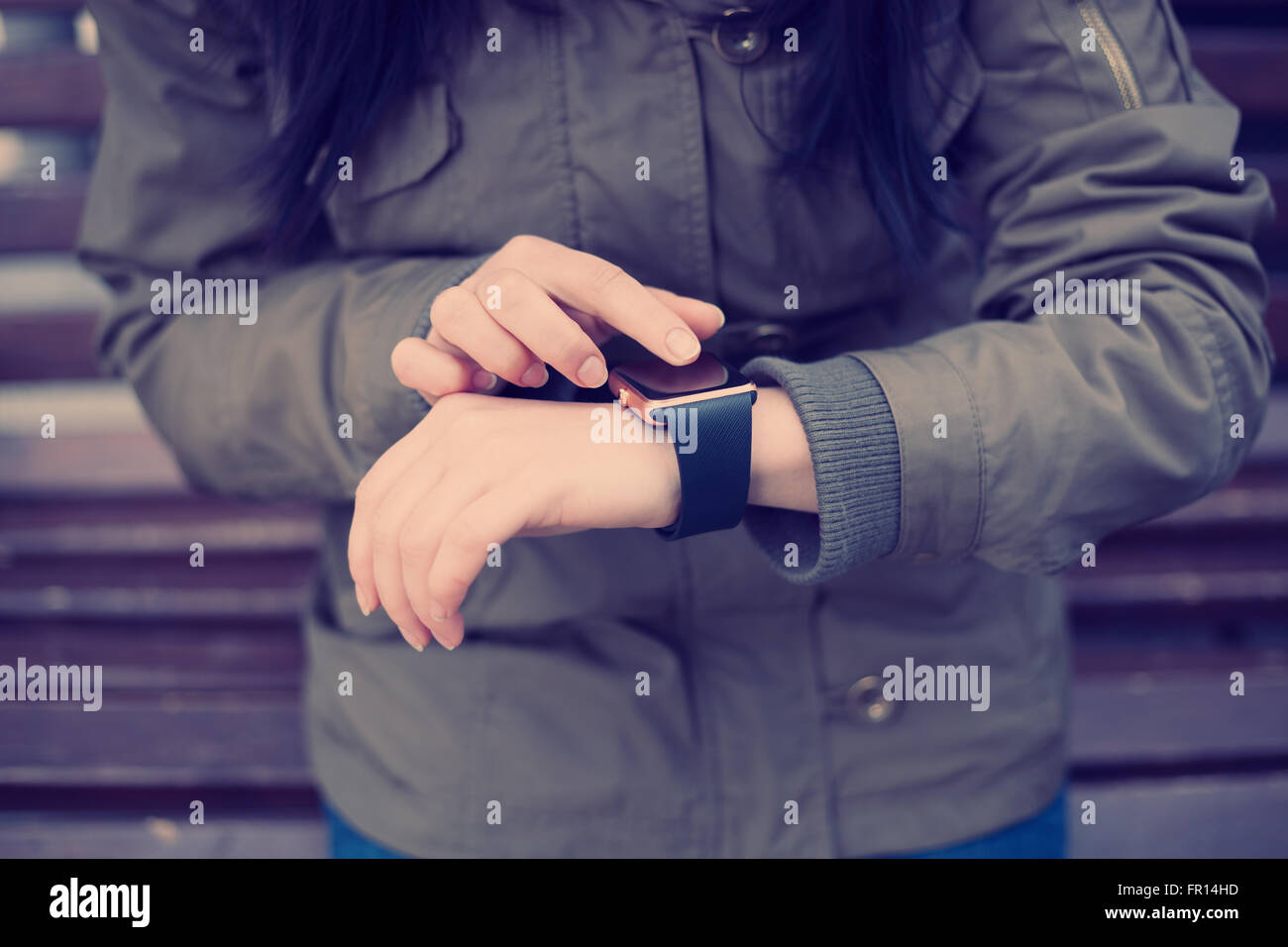 Female reading new messages on her trendy smart wrist watch, touching it with a finger. This person is always connected Stock Photo