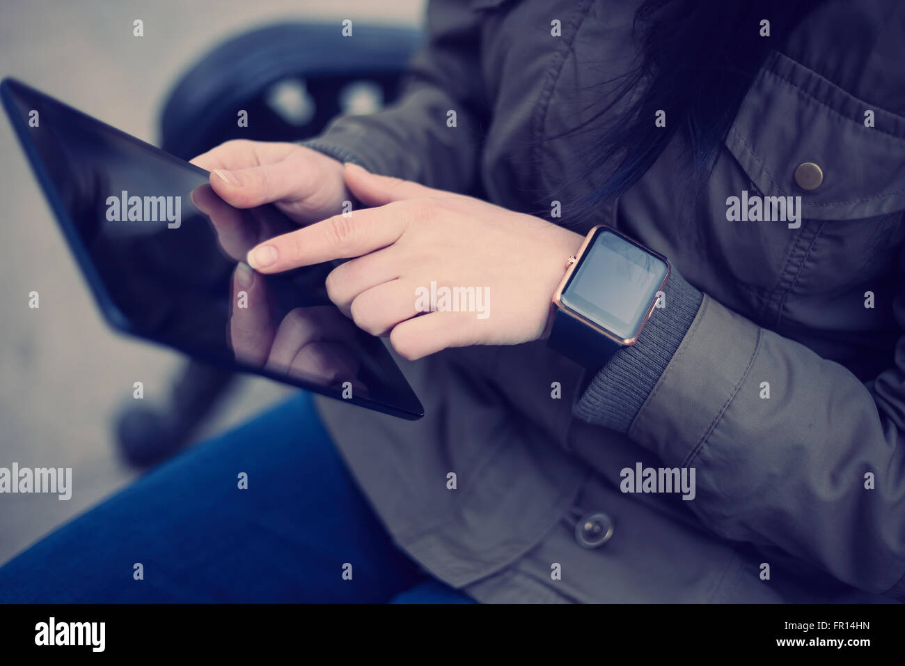 Female using a tablet pc while wearing her trendy smart wrist watch, focus on the gadgets. This person is always connected to so Stock Photo