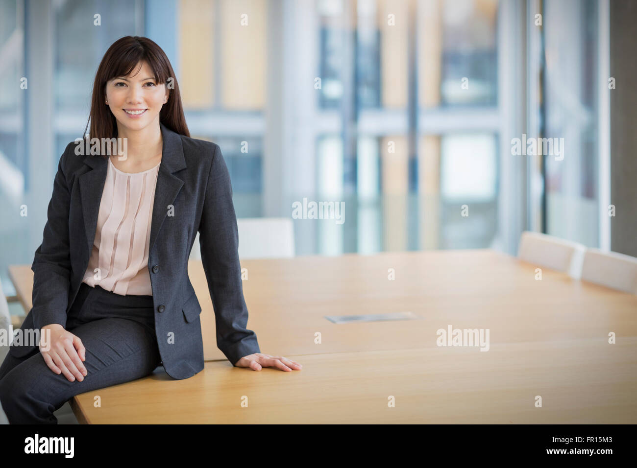 Portrait smiling businesswoman leaning on conference table Stock Photo