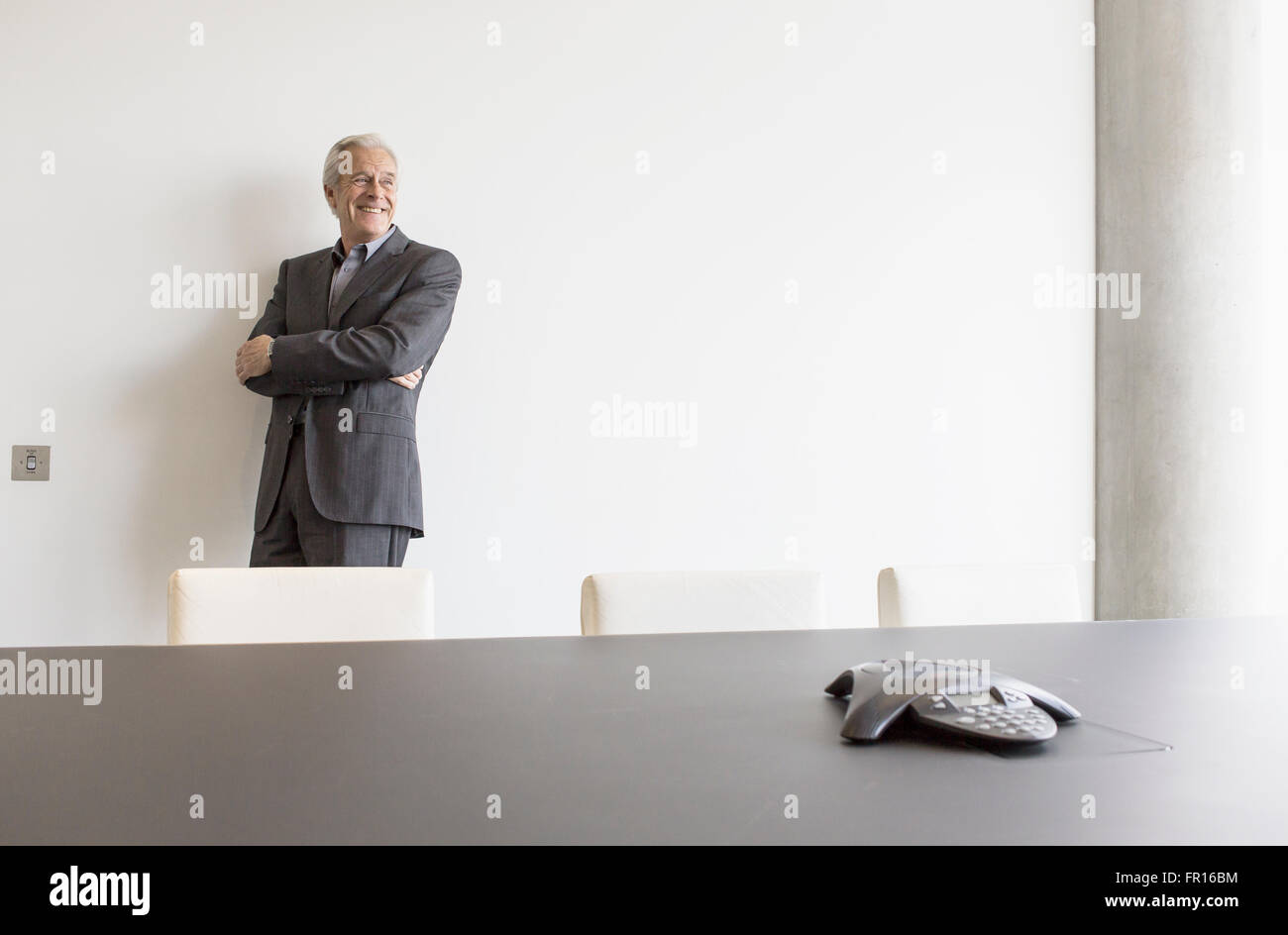 Smiling senior man looking away in conference room Stock Photo