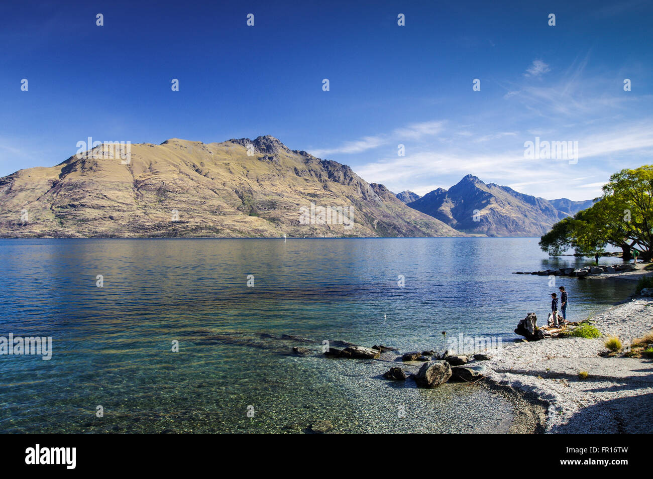 Pair of children playing at the shores of Lake Wakatipu - Queenstown, New Zealand Stock Photo
