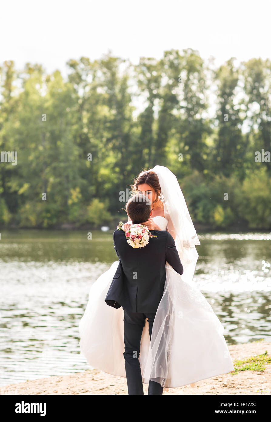 Wedding couple standing and kissing near lake Stock Photo - Alamy