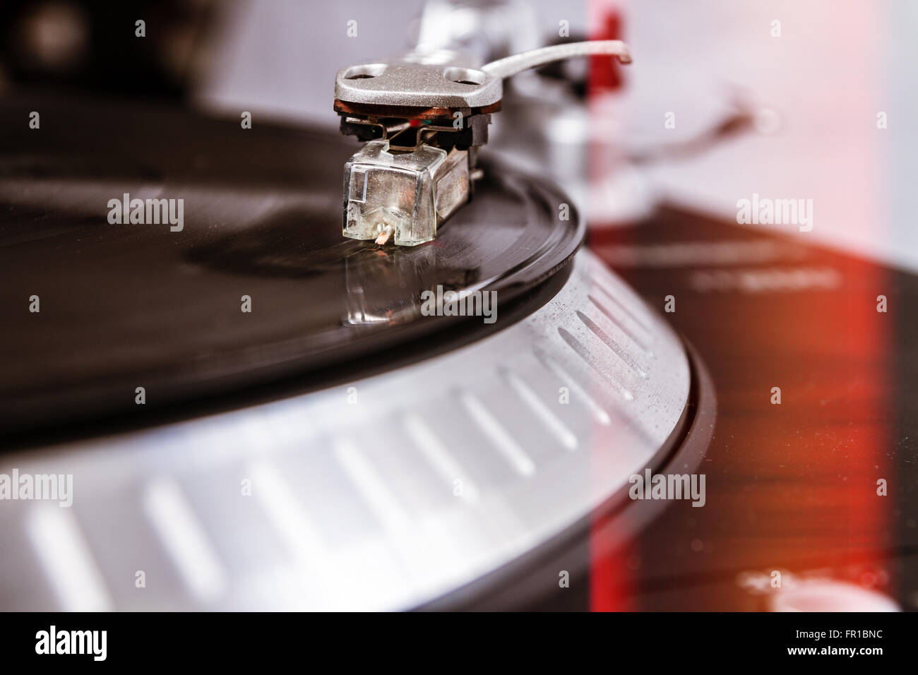 Professional turntable playing vinyl records with music. Close up on details : needle, tonearm, platter, vinyl record Stock Photo