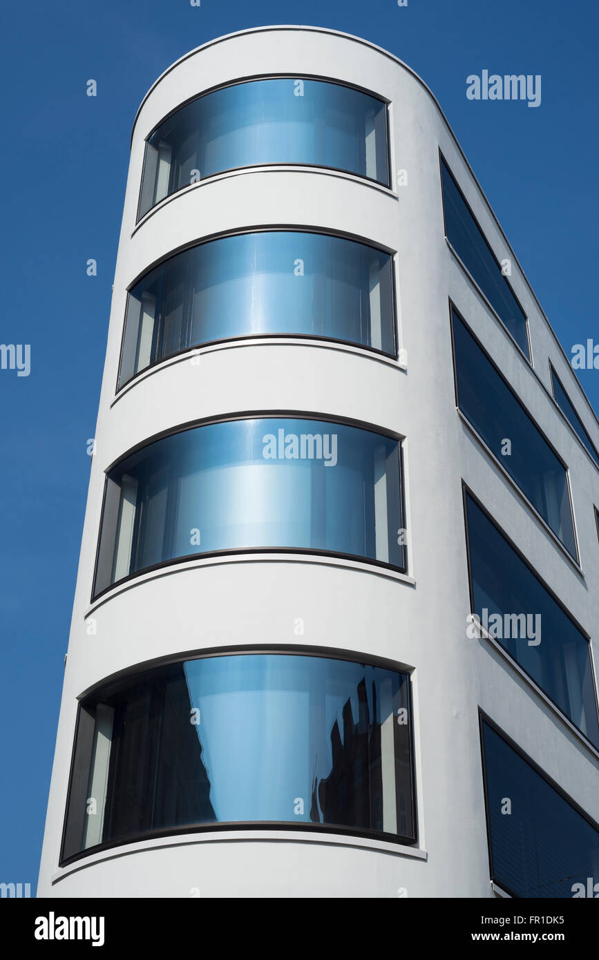 Modern architecture and facade with curved glass windows in a building's corner in Munich, Bavaria, Germany Stock Photo