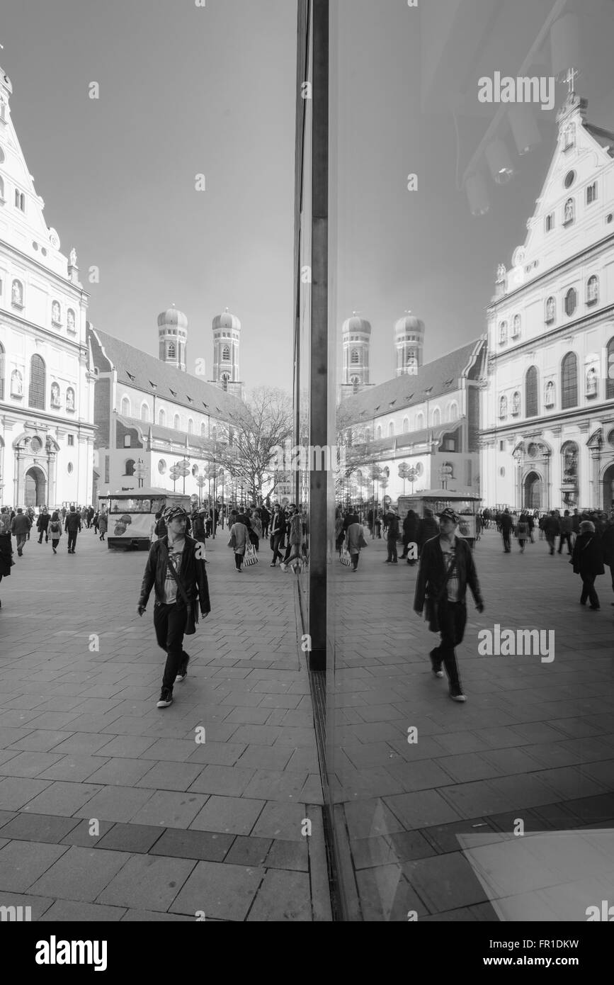 Young man looks in a store entrance in the pedestrian area of Munich being symmetrically mirrored in the shop window Stock Photo