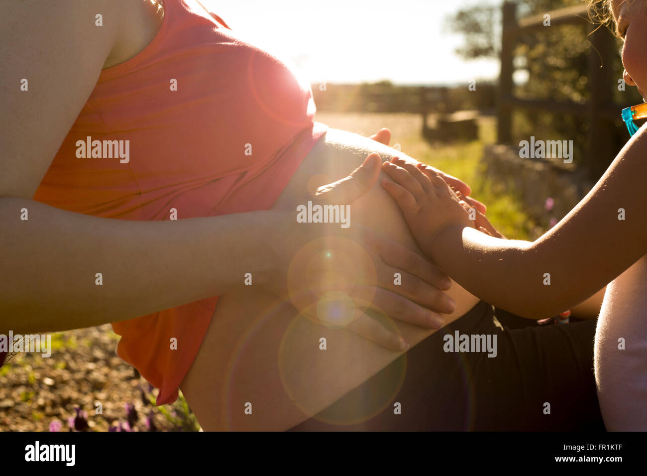 Pregnant mother and her little daughter expecting newborn brother at nature environment Stock Photo
