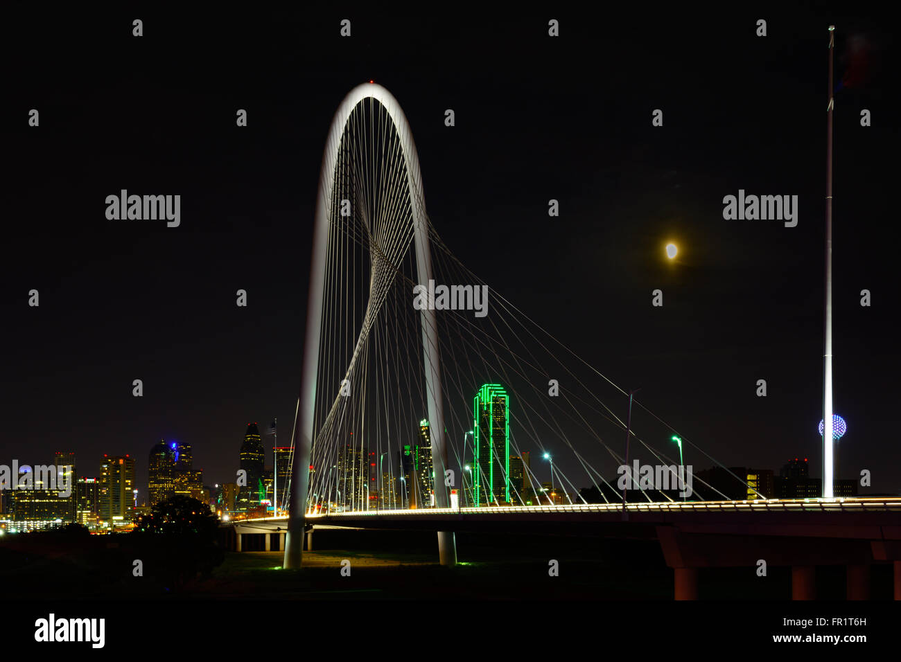 Dallas, Texas Skyline Nightscape with bridge in the foreground and moon in sky. Margaret Hunt Hill Bridge Showcases nightscape during lunar eclipse Stock Photo