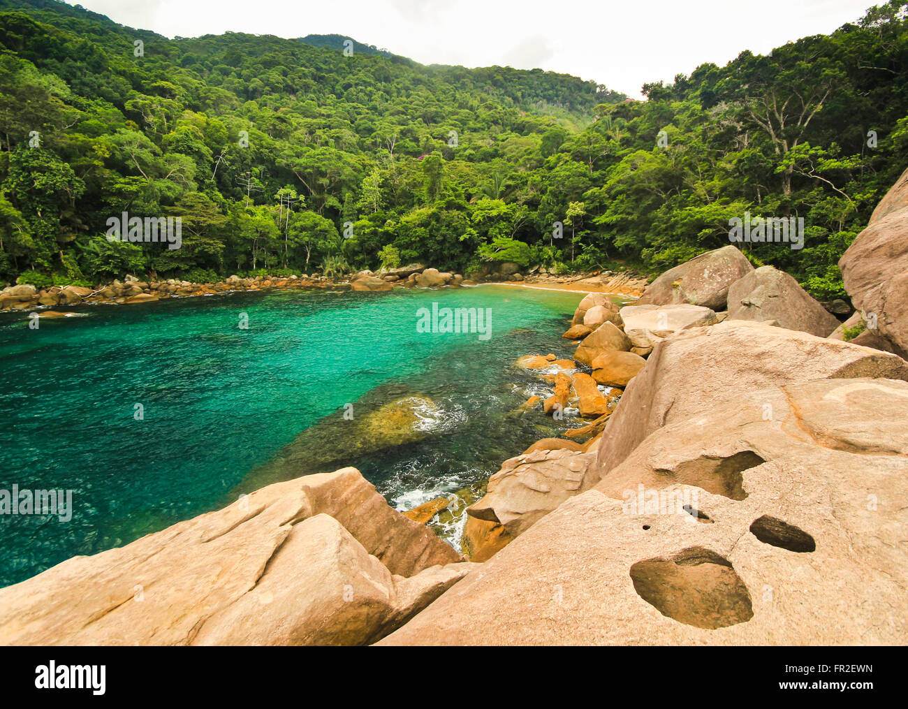 tropical beach with green water, stones on shore and bottom Stock Photo