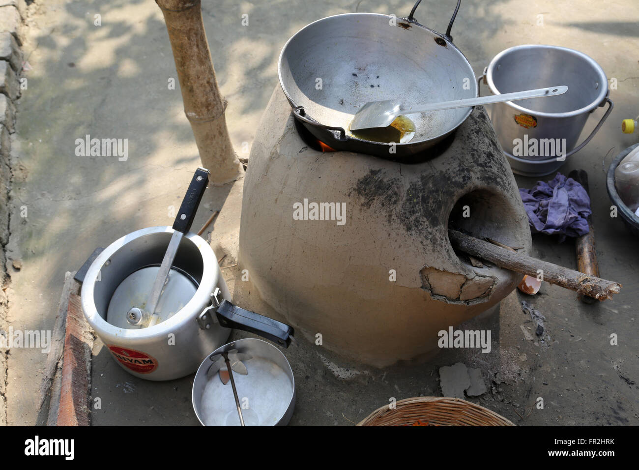 Mud kitchen stove in village outside home. Remnants of firewood, ashes