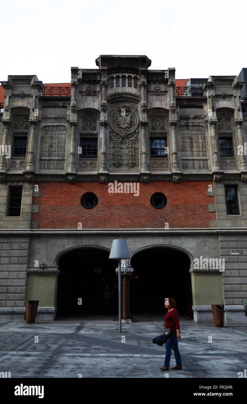 Local woman walking past side wall of the Alhondiga building, now the Azkuna Zentroa cultural centre, Bilbao, Basque Country, Spain Stock Photo