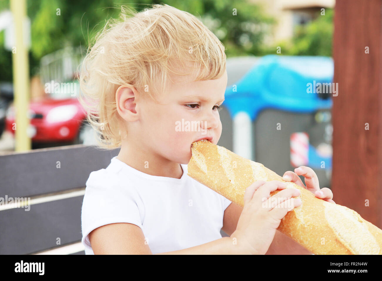 Outdoor closeup portrait of cute Caucasian blond baby girl eating ...