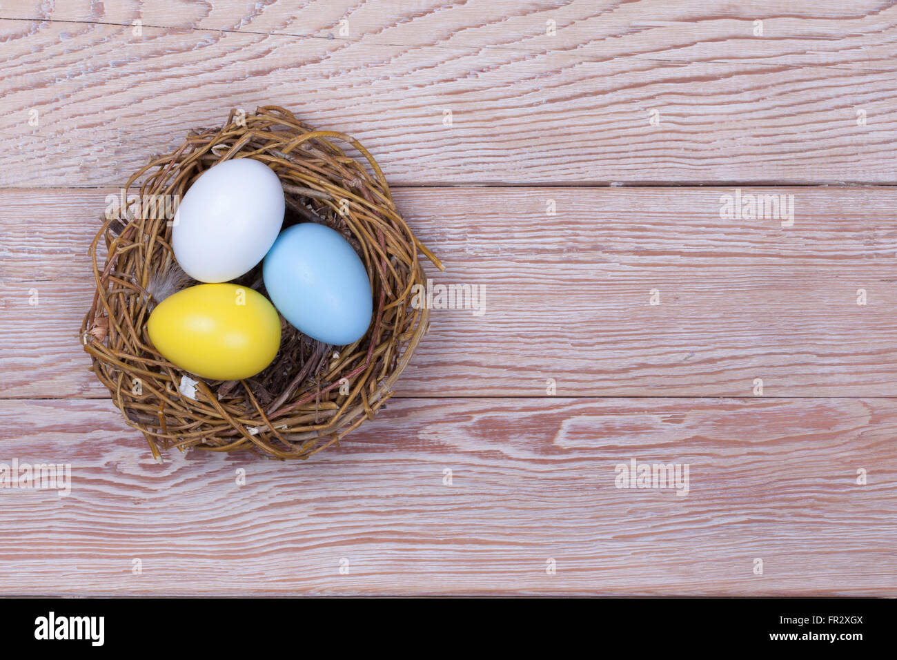 Three Easter colorful eggs in bird nest on wooden background Stock ...