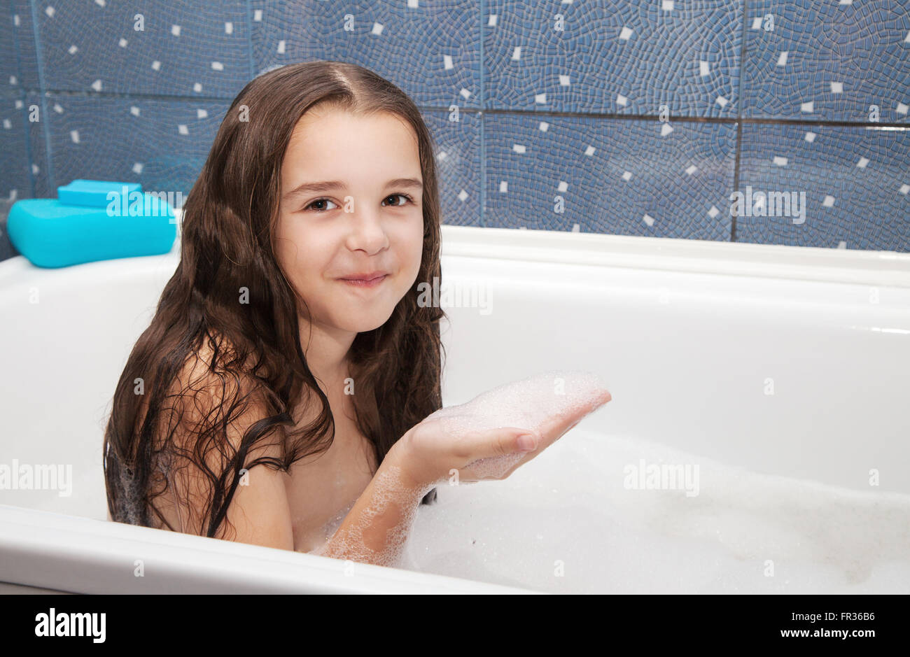 little smiling girl with long brown hair taking a bath with shampoo ...