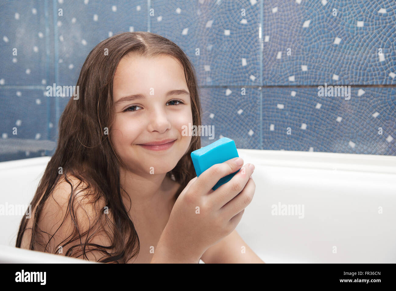 little smiling girl with long brown hair holding soap sitting in the ...