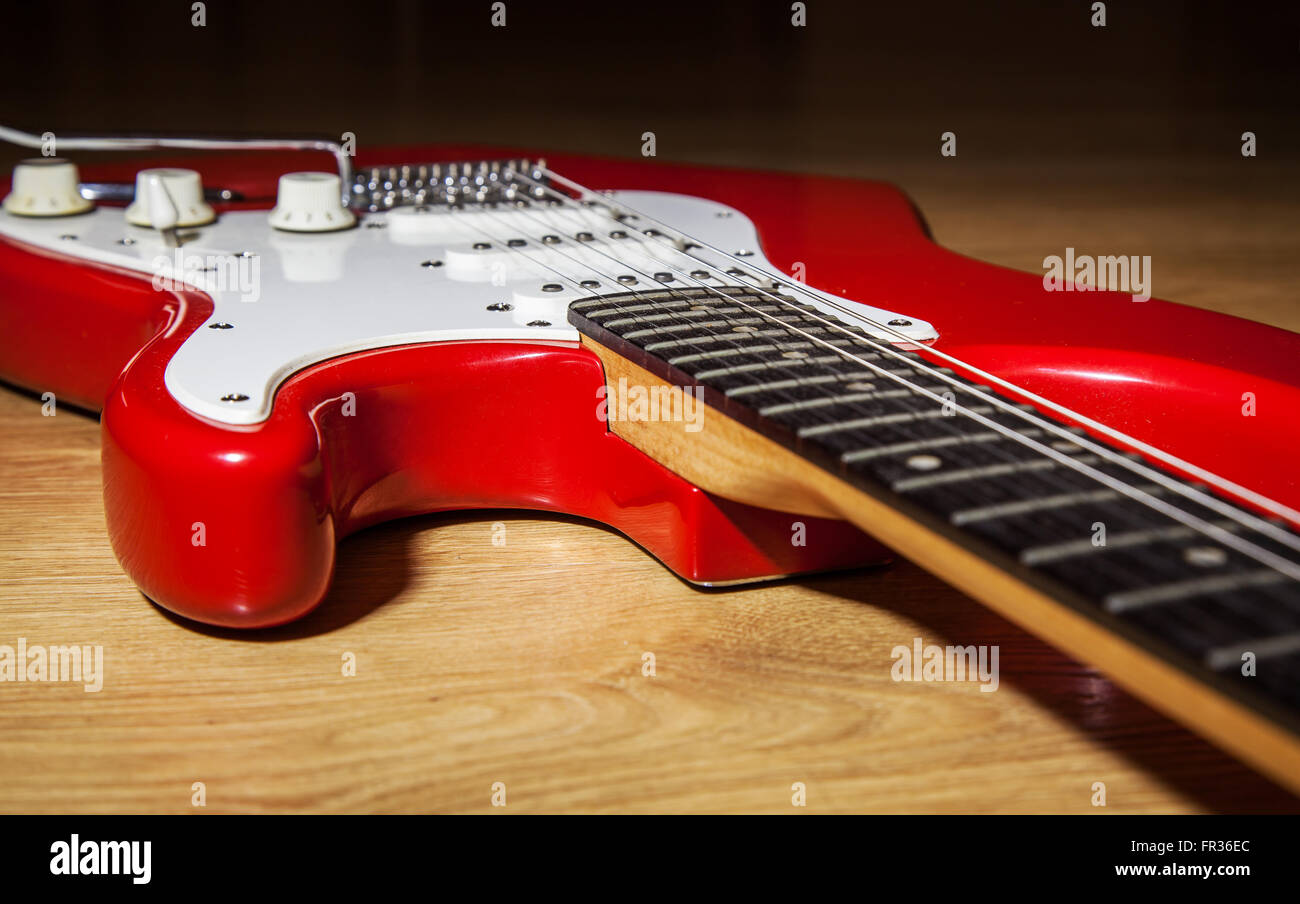 body part of red 6 string electric guitar lying on the wooden floor