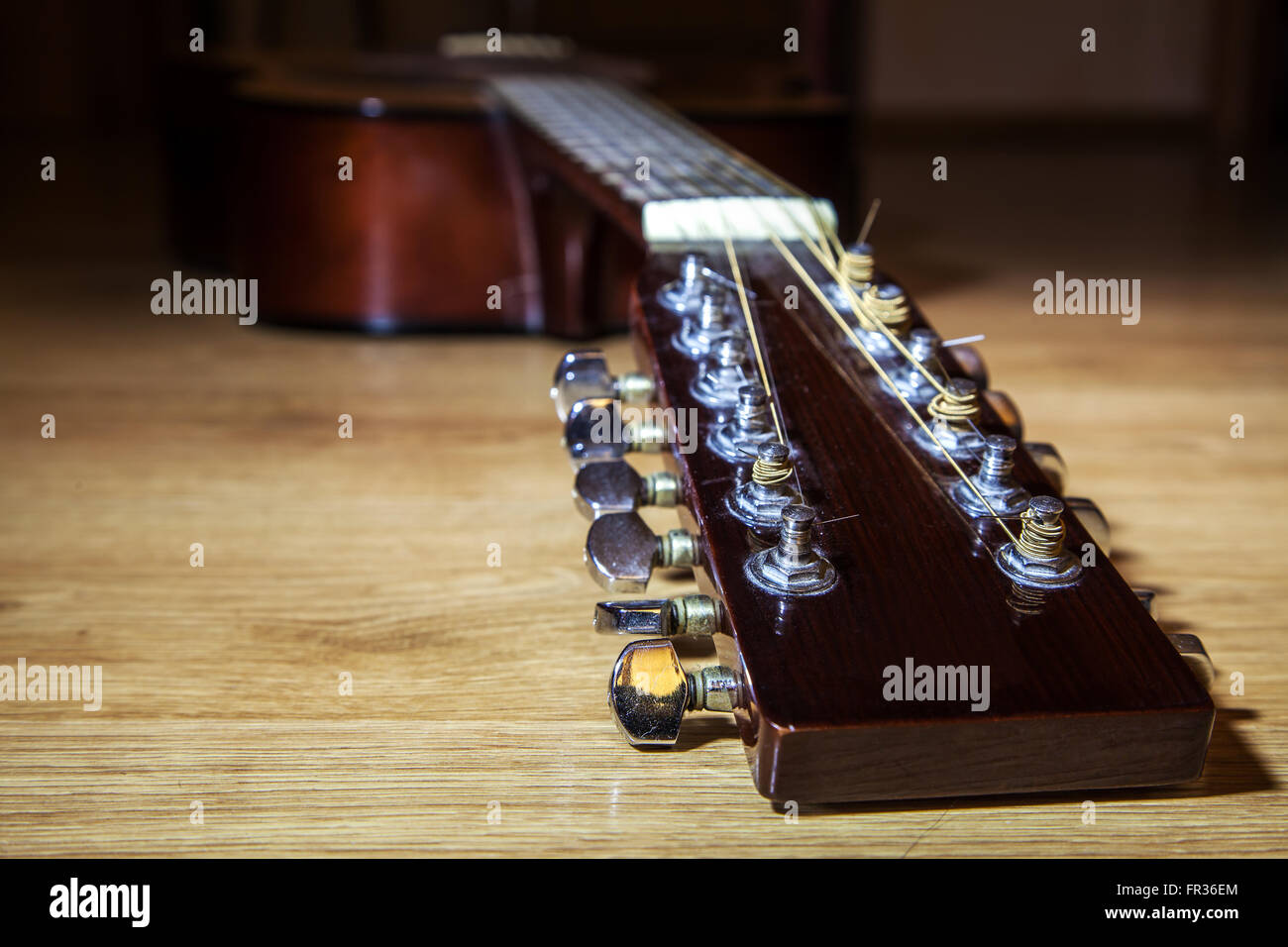 brown head neck of 12 string guitar lyinh on wooden floor closeup Stock Photo