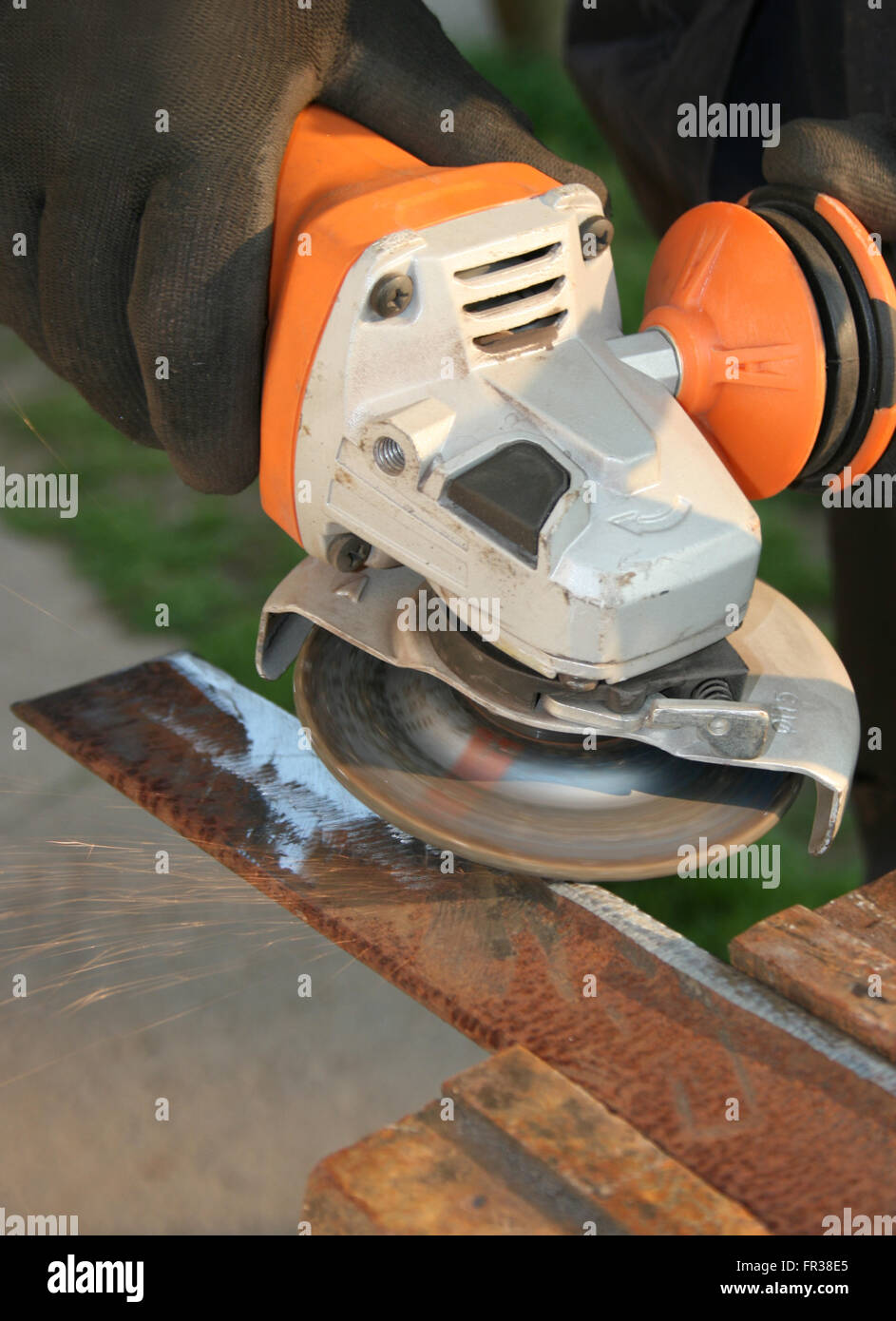 Grinding a metal part wearing standard protection equipment Stock Photo