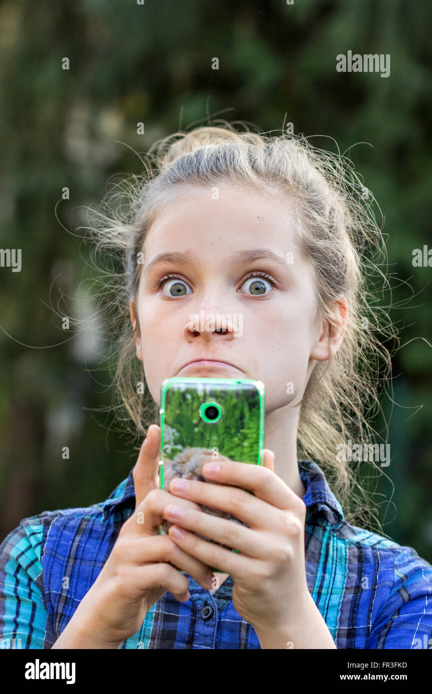a young girl looking surprised at her cell phone Stock Photo