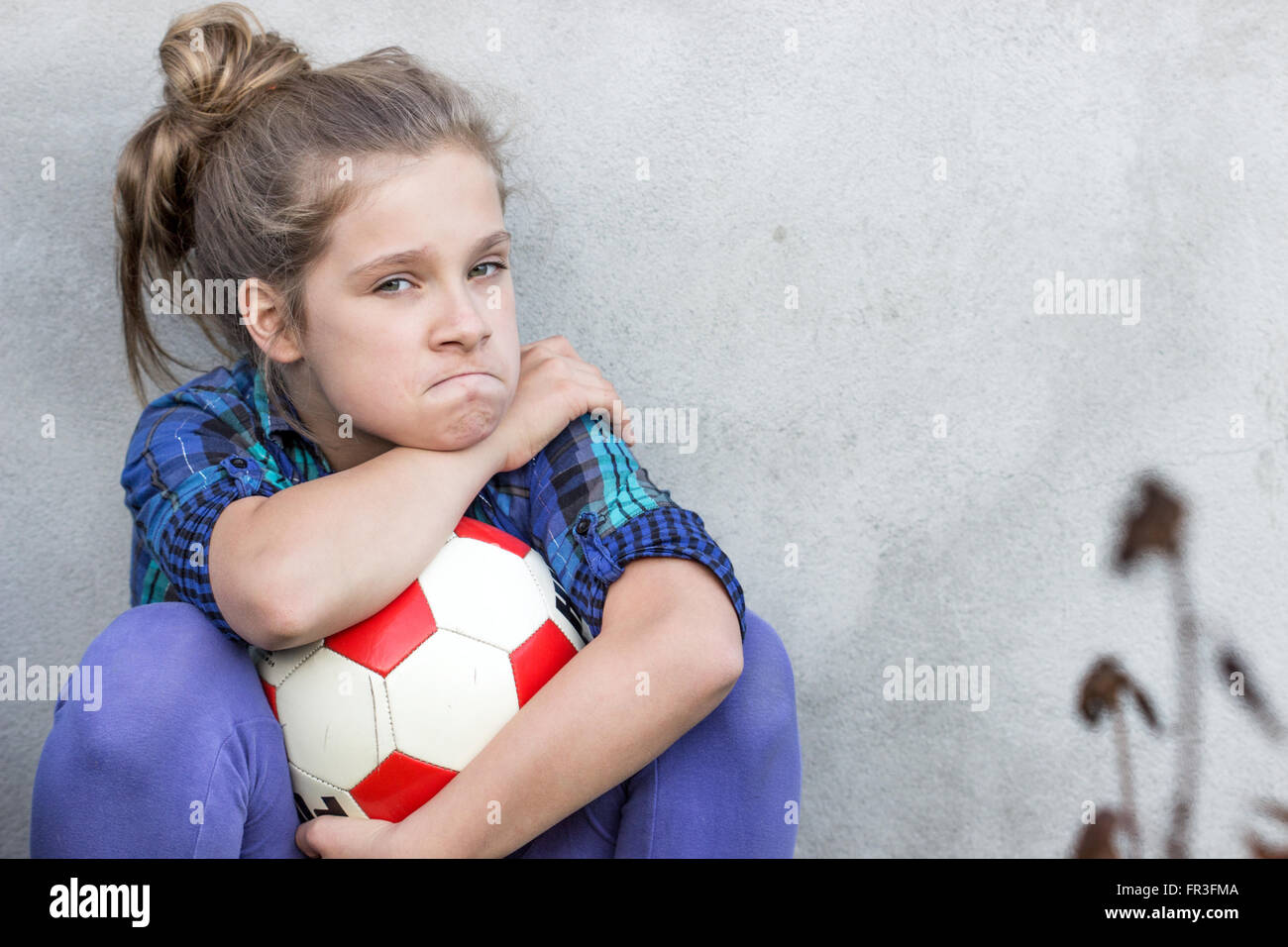 A young girl holds a ball angrily fixed Stock Photo
